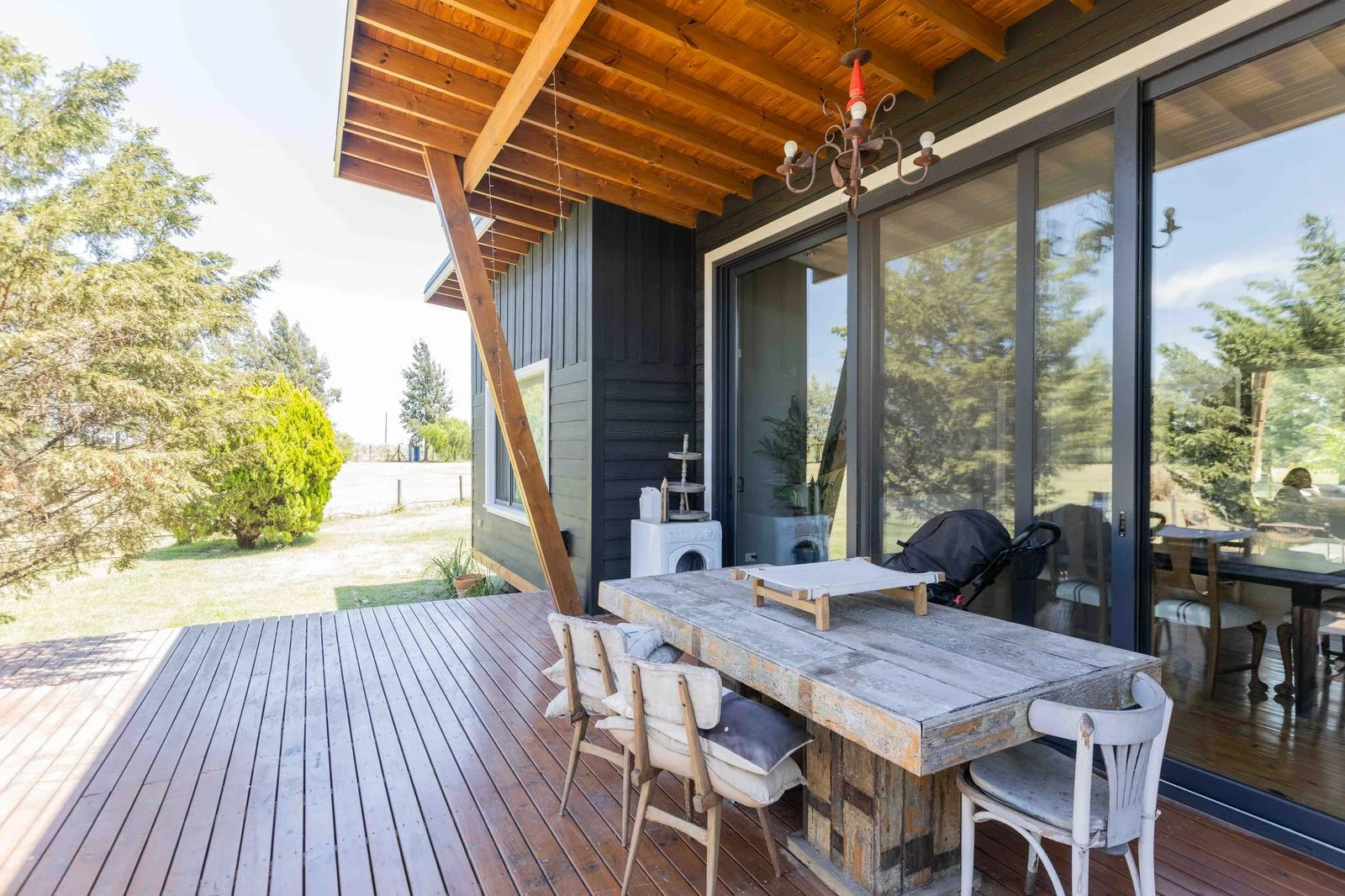 Galería de madera con mesa, sillones y salida al parque