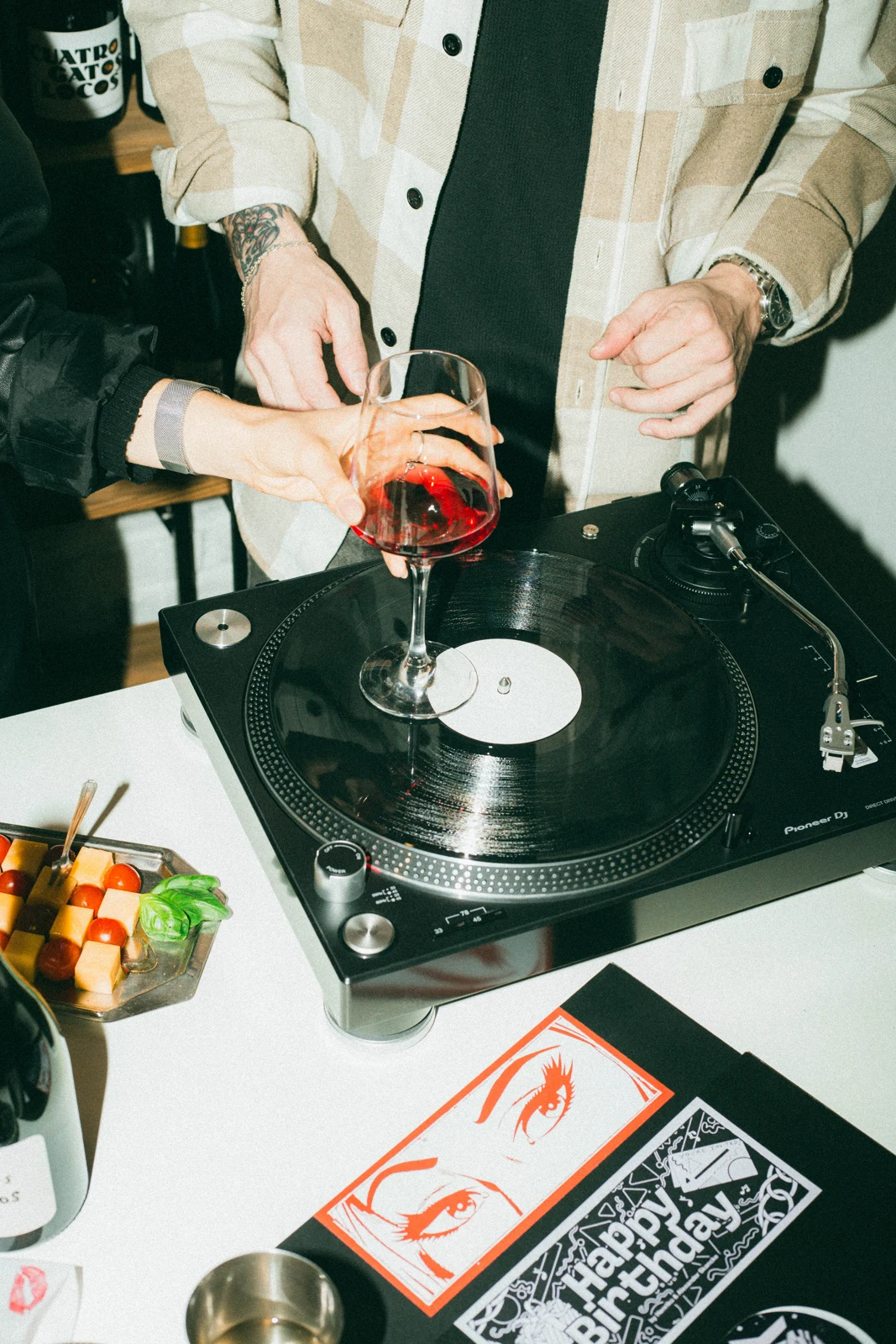 Copas de vino junto a un tocadiscos y discos de vinilo